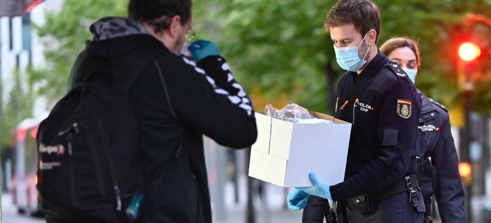 Foto portada: un agent de la Policia Nacional repartint mascaretes, aquest dilluns a Madrid. Autor: Moncloa. 