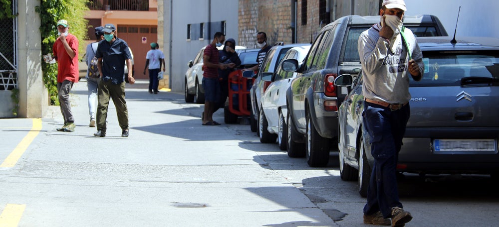 Pla obert on es poden veure diversos temporers amb mascareta en un carrer d'Aitona, el 13 de juliol de 2020. (Horitzontal)