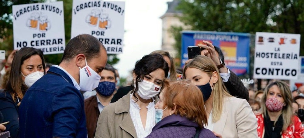 Díaz Ayuso en un acte. Al darrera cartells agraïnt-li no haver tancat la restauració. Font: Isabel Díaz Ayuso via Twitter. 