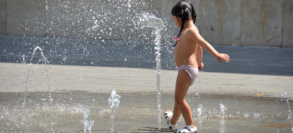 Una nena es refresca a la font de la plaça Sant Roc. Autor: David B.