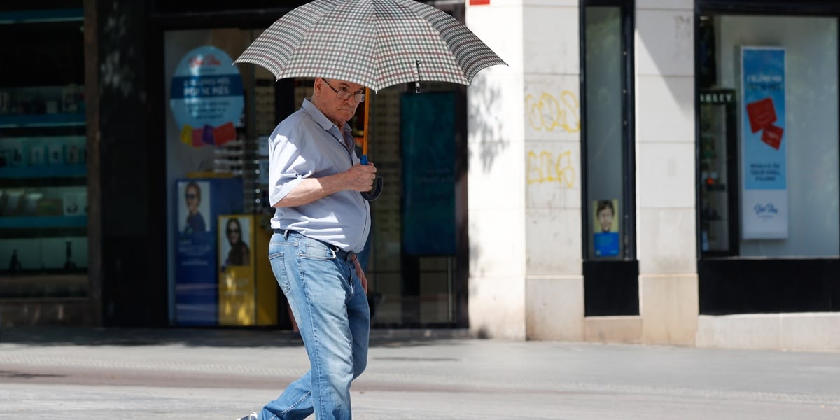 Un home amb paraigues per protegir-se del sol. Autor: David Jiménez.