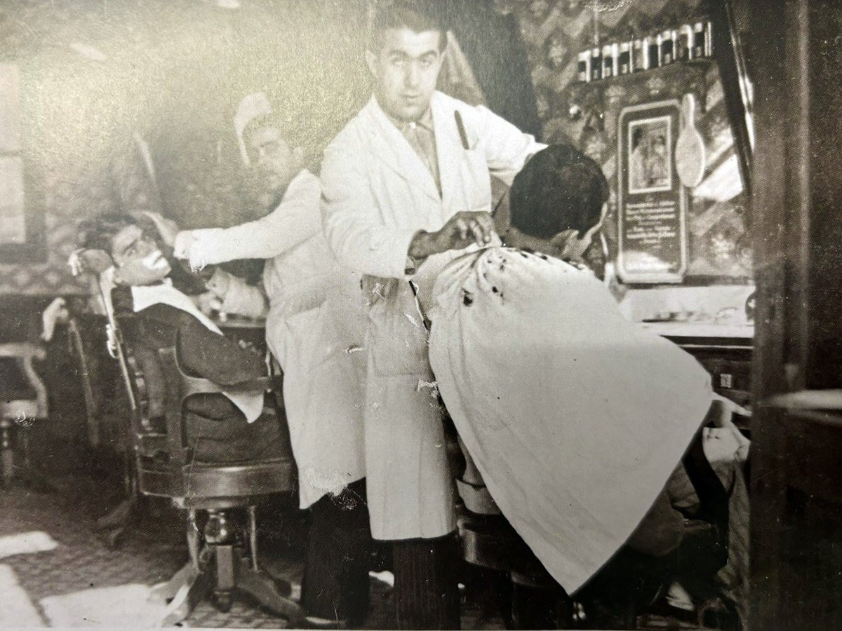 Barberia del carrer de Margenat, 4, cap al 1935. Ricard Simó Bach, el propietari, talla els cabells a Agustí Castells mentre un ajudant afaita un altre client. Autor desconegut. Fons: Josep Simó Deu via 'L'Abans de Sabadell'. 