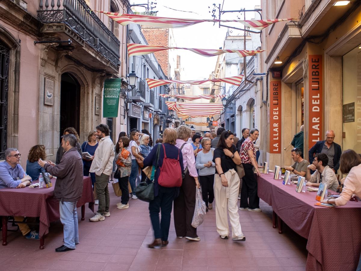 El carrer Sant Antoni, engalanat amb senyeres, ple per a les signatures de La Llar del Llibre.