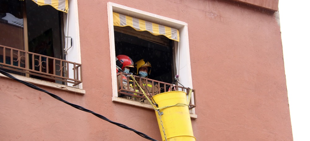 Pla detall de dos bombers a la finestra de l'immoble afectat per un ensorrament parcial al barri de Can Rull, a Sabadell, el 8 de febrer de 2021. (Horitzontal)