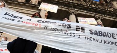 Pla contrapicat dels treballadors de Correus de Sabadell protestant amb una pancarta davant la seu de l'empresa a Barcelona, el dia 11 de maig de 2021. Autor: ACN.