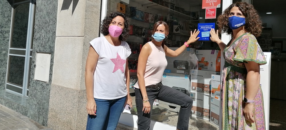 Foto portada: Montse González, Marta Farrés i Encarna, propietaria d'Infoexpress, enganxen l'adhesiu Cuida'm. Autor: Ana.M