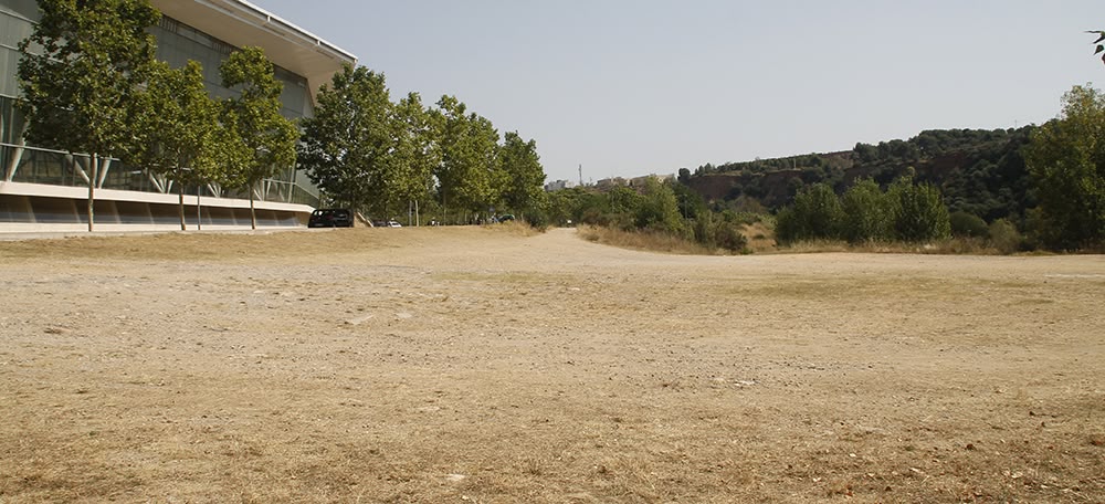 El solar on es vol construir una piscina d'onades, al costat de la Bassa, davant la Pista Coberta i darrera del riu Ripoll, el 5 de juliol. Autora: Lucía Marín.