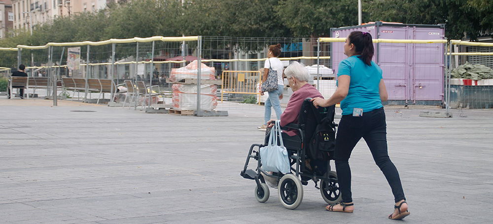 Una dona passejant una senyora amb cadira de rodes. Autora: Lucia Marin