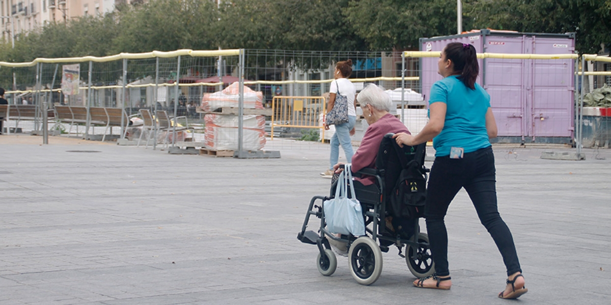 Una dona passejant una senyora amb cadira de rodes. Autora: Lucia Marin
