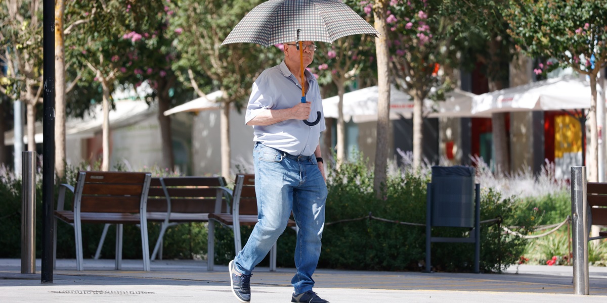 Un home amb paraigues per protegir-se del sol. Autor: David Jiménez.