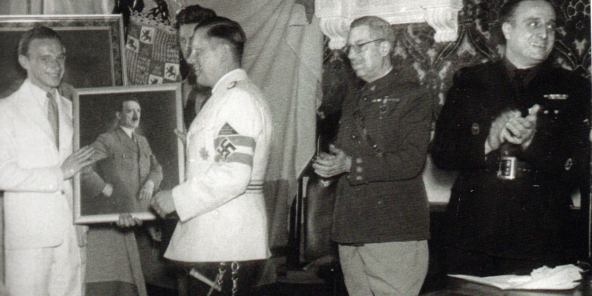 Entrega del retrato de Hitler. Elhers de blanco con la esvástica, el coronel Feijóo y el alcalde Marcet (1941). Autor desconocido/AHS.