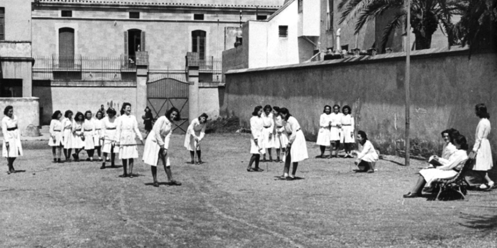 Grup de nenes, alumnes del “Colegio de Bachillerato de Sabadell”, jugant a críquet al pati de l’escola. Edifici de l’Escola Industrial, inicis dècada 1940. Autor: desconegut (AHS).