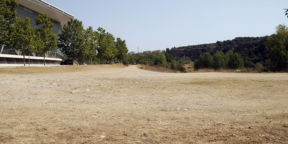 El solar on es vol construir una piscina d'onades, al costat de la Bassa, davant la Pista Coberta i darrera del riu Ripoll, el 5 de juliol. Autora: Lucía Marín.